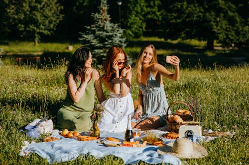 A Woman Holding Her Mobile Phone while Taking Picture with Her Friends