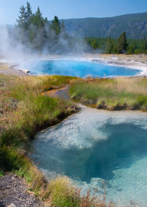 Free Stunning view of a steaming blue geyser surrounded by natural landscape in Yellowstone National Park. Stock Photo