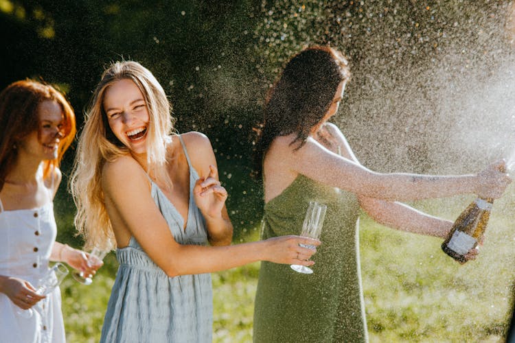 Women Having Fun While Splashing Liquid From The Bottle