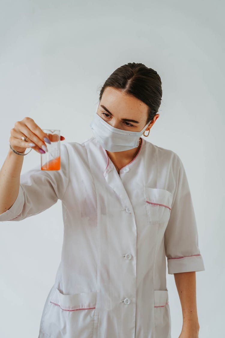 Woman In White Lab Gown Wearing Face Mask While Holding A Test Tube