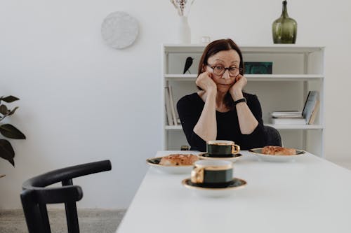 An Elderly Woman Wearing Eyeglasses while Looking at the Table