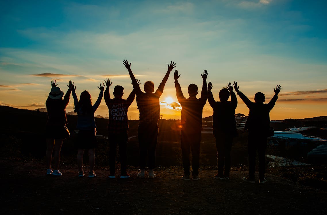 groupe face au soleil couchant les bras vers le ciel