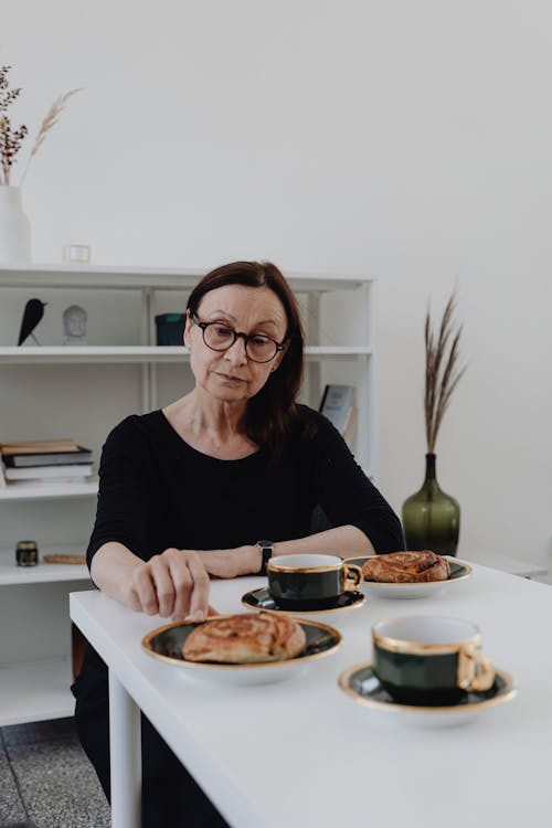 A Sad Woman in Black Long Sleeves Sitting while Looking at the Food on the Table