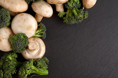 Free Close-Up Shot of Broccoli and Mushrooms on a Black Surface Stock Photo