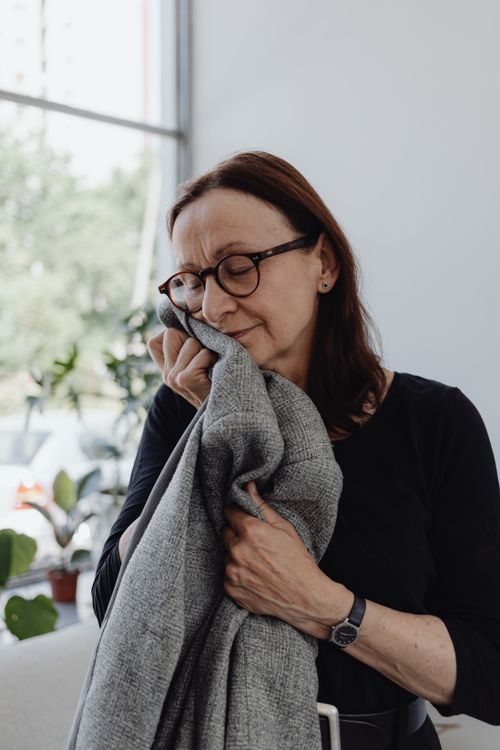 Free Emotional portrait of a woman grieving indoors, holding blankets closely. Stock Photo