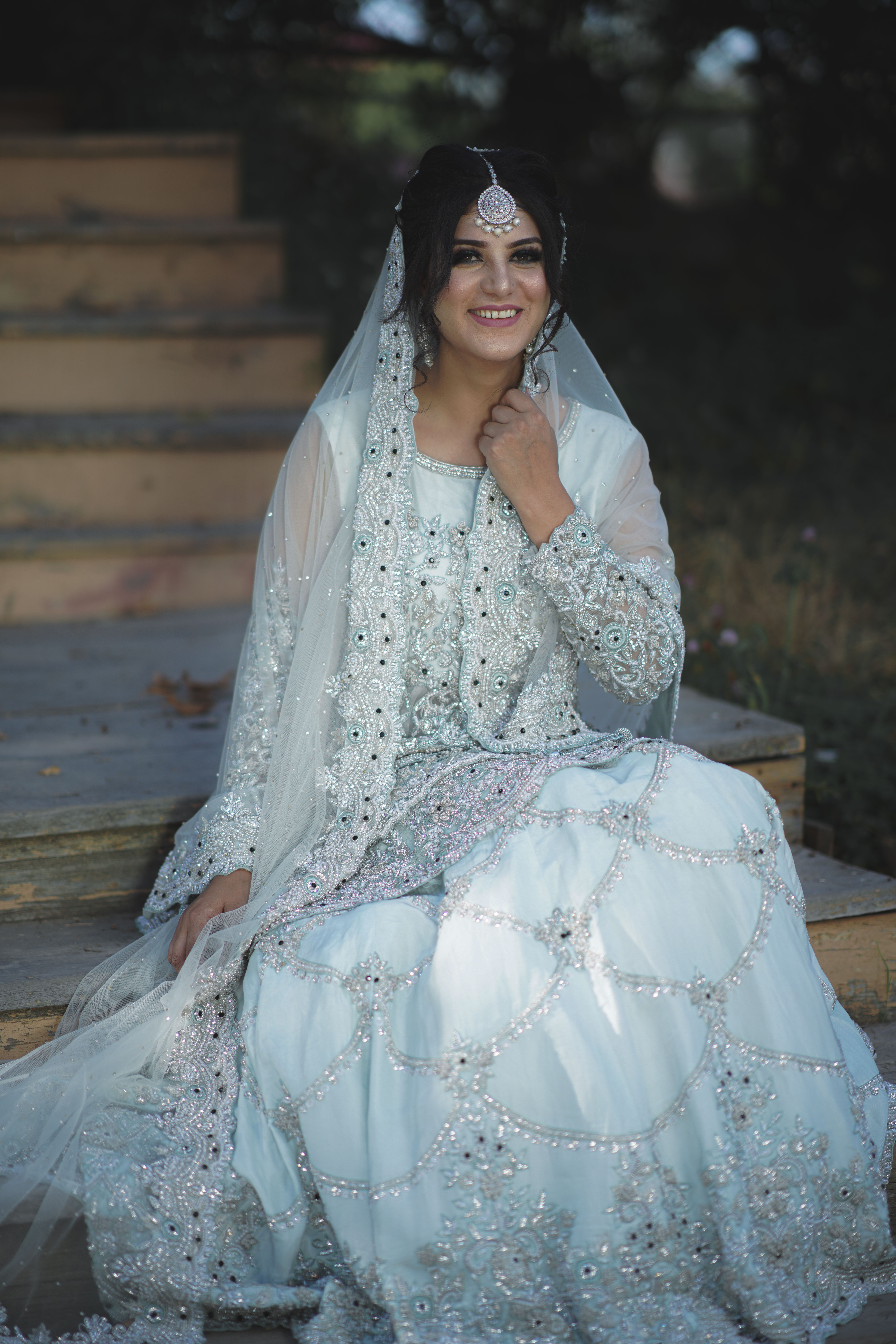 Beautiful Indian bride in traditional attire sitting outdoors on wooden stairs in Kashmir.