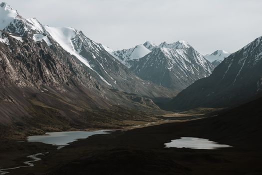 Scenic view of a majestic snow-capped mountain range with serene lakes and lush valleys.