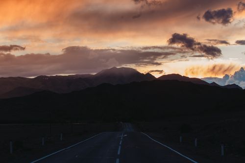 Free A breathtaking view of a mountain road against a vibrant sunrise sky, capturing nature's beauty. Stock Photo