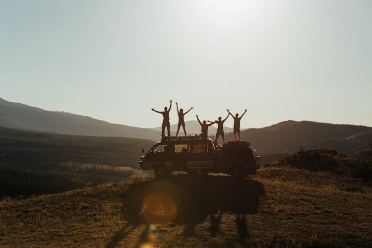 Silhouette Of People Standing On The Roof Of A Van 