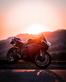 A sleek sports motorcycle parked on a road against a stunning sunset backdrop.