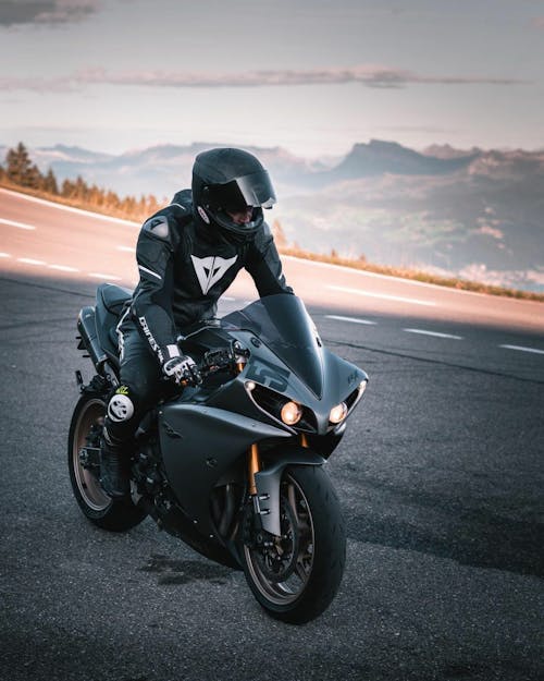 A Person in Black Helmet Riding a Black Sports Bike on the Road