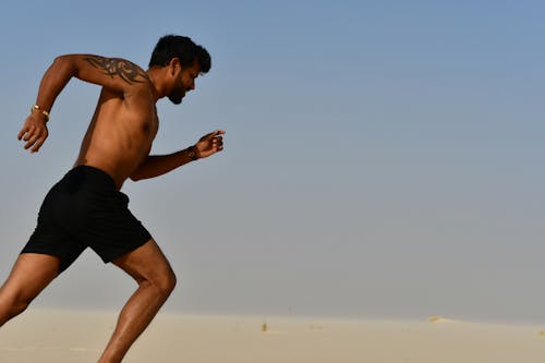 ورزشکار قوی بدون پیراهن دویدن در یک روز روشن