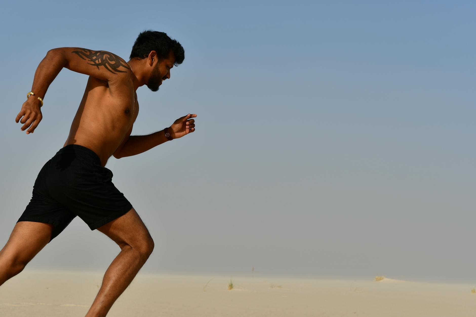 Strong shirtless sportsman jogging on bright day