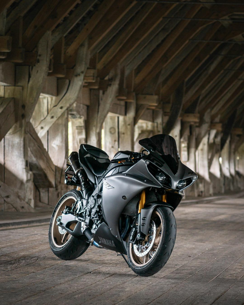 Free A sleek Yamaha motorcycle parked under a rustic wooden structure, showcasing modern design. Stock Photo