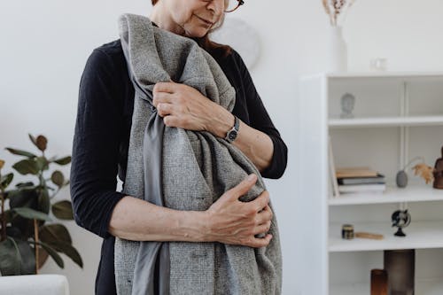 An Elderly Woman in Black Long Sleeves Embracing Her Coat