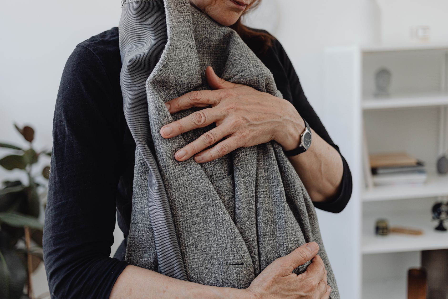 Close-up of a hand pinching the chest of a wool blazer to feel for a distinct interlining layer.