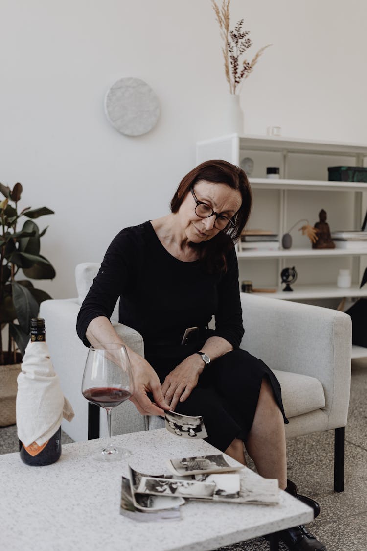 A Woman In A Black Dress Looking At Pictures