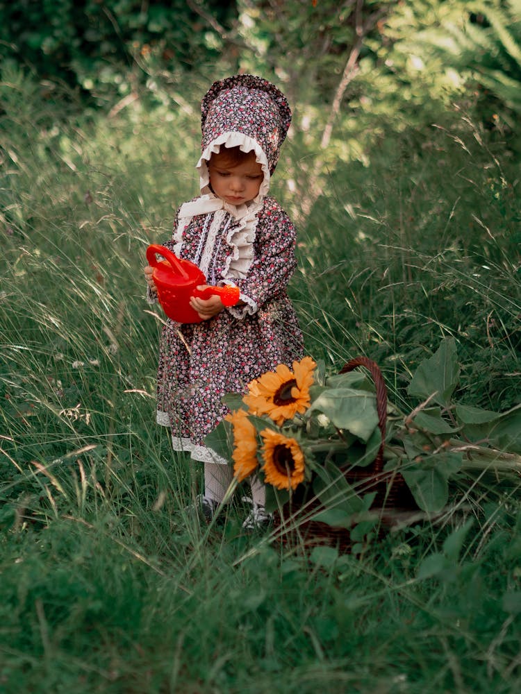 Cute Little Girl Holding A Watering Can Over Sunflowers 