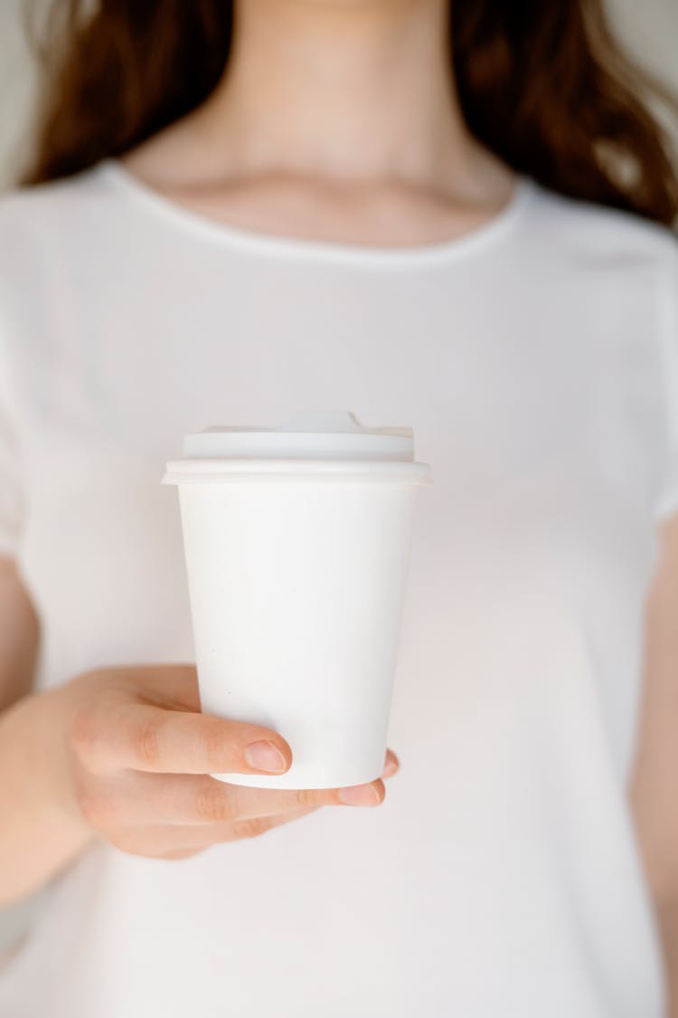 Person Holding A White Cup