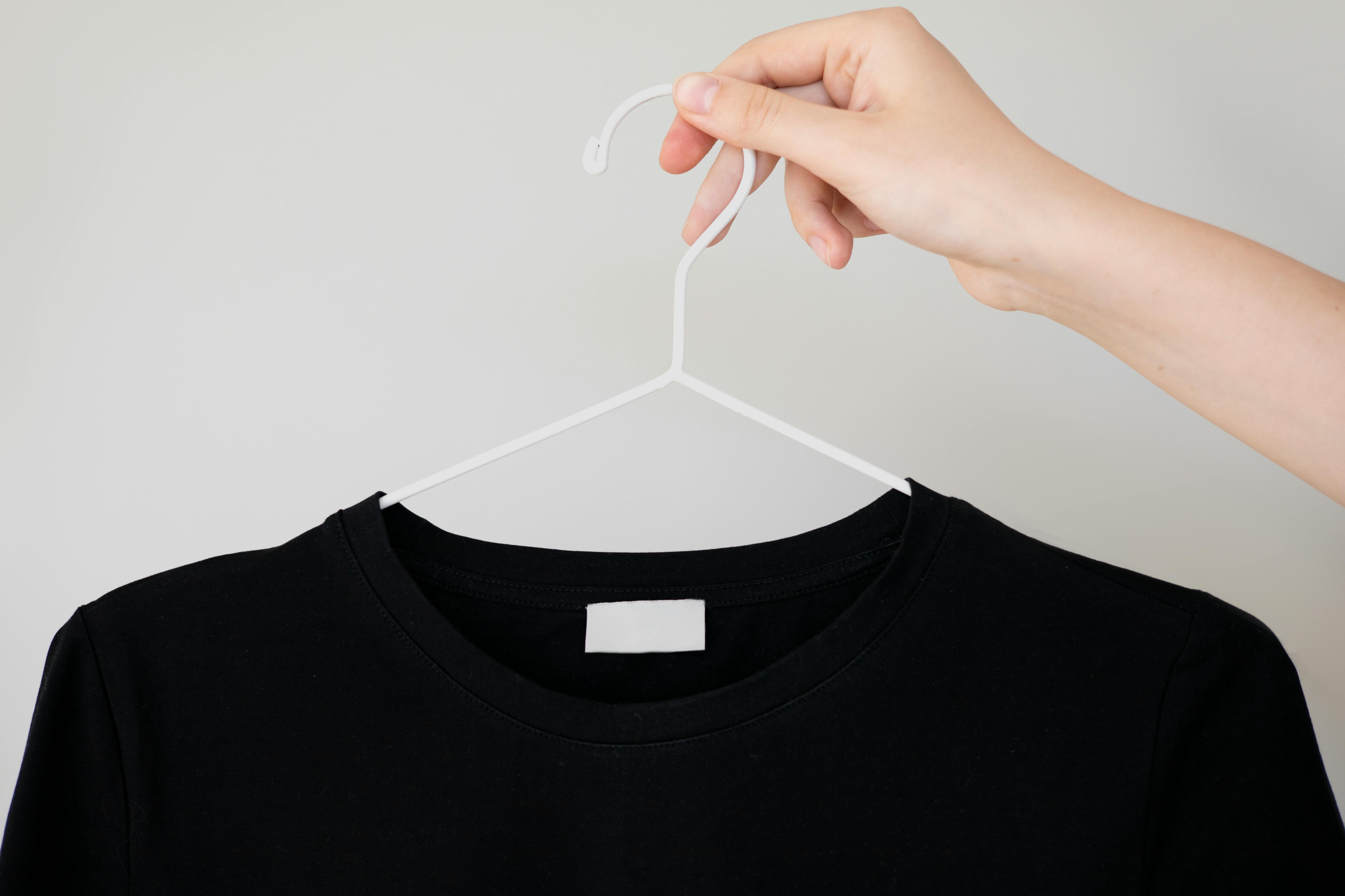 A person holding a hanger with a shirt