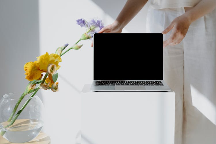 Person Holding A Laptop Beside A Flower