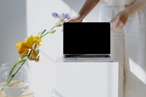 Free Minimalist workspace featuring a laptop and colorful flowers, perfect for creative inspiration. Stock Photo