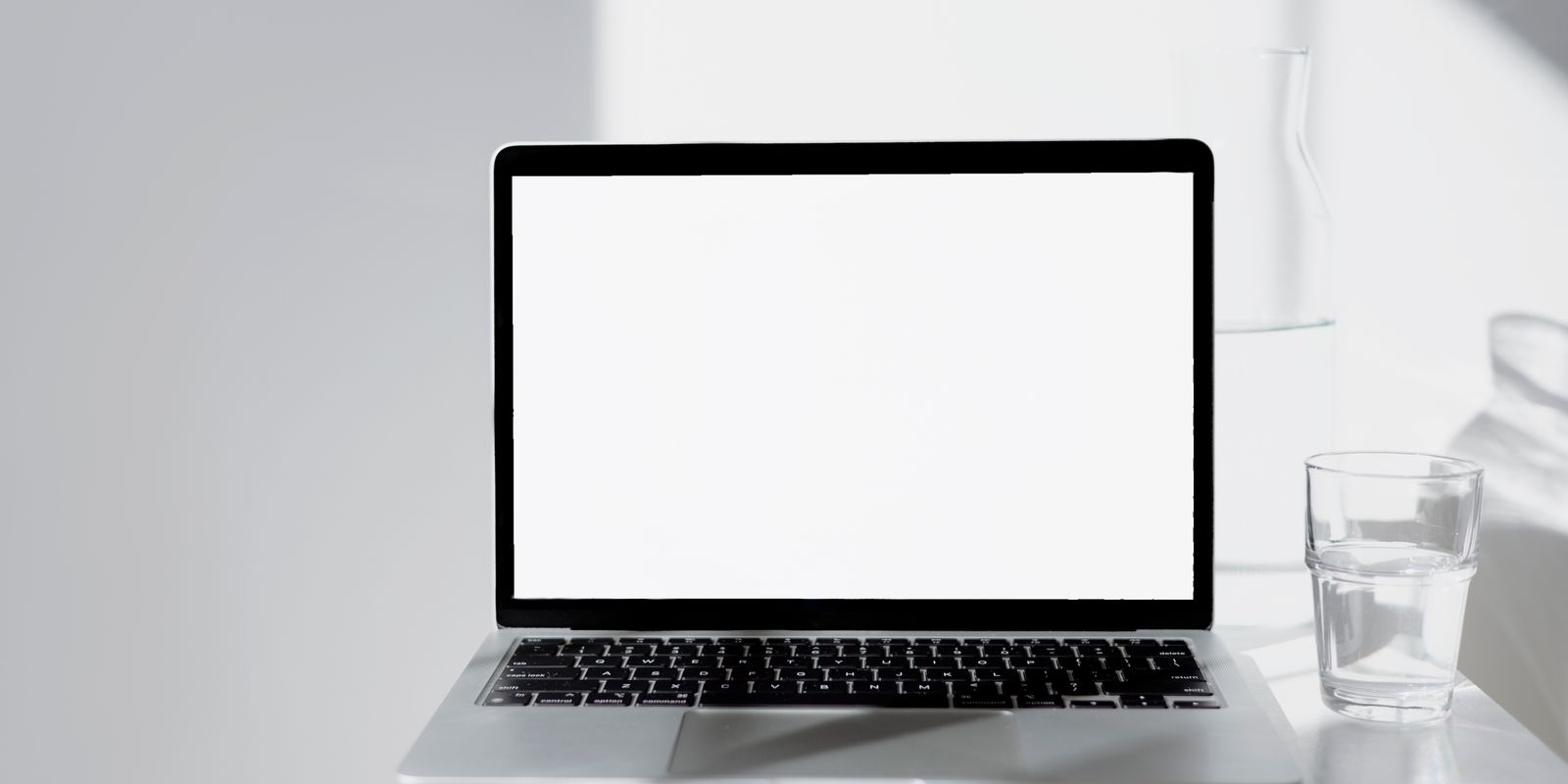 A laptop with a blank white screen on a minimal desk