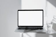 A Close-Up Shot of a Laptop Beside a Glass of Water