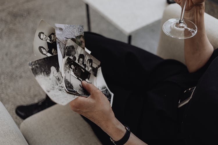 Person Holding Photographs While Sitting On The Sofa 