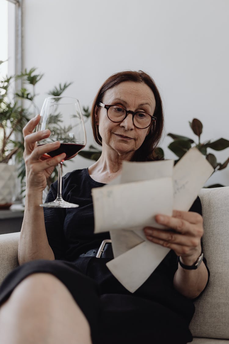 A Woman Having Red Wine While Looking At Pictures