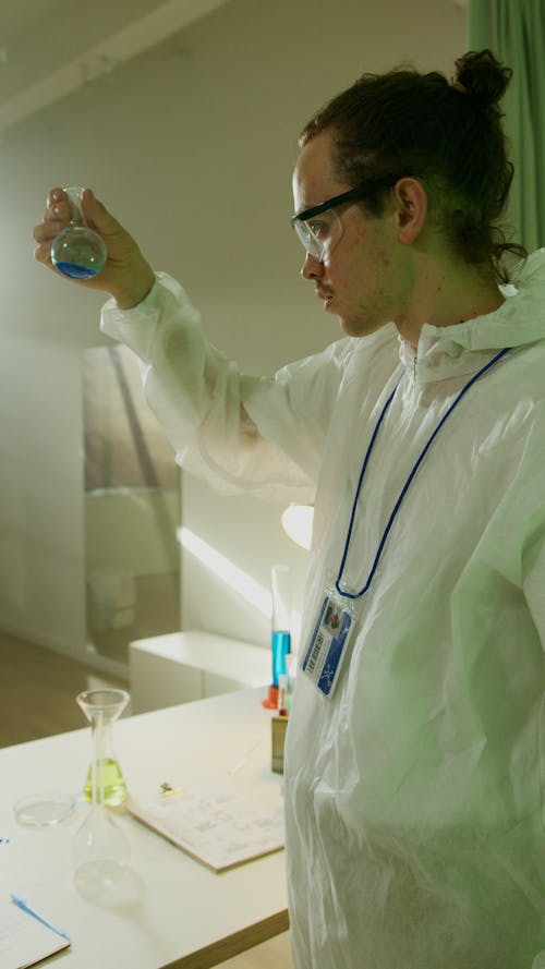 A Chemist Looking at a Chemical on a Glass Tube Doing Research in a Laboratory