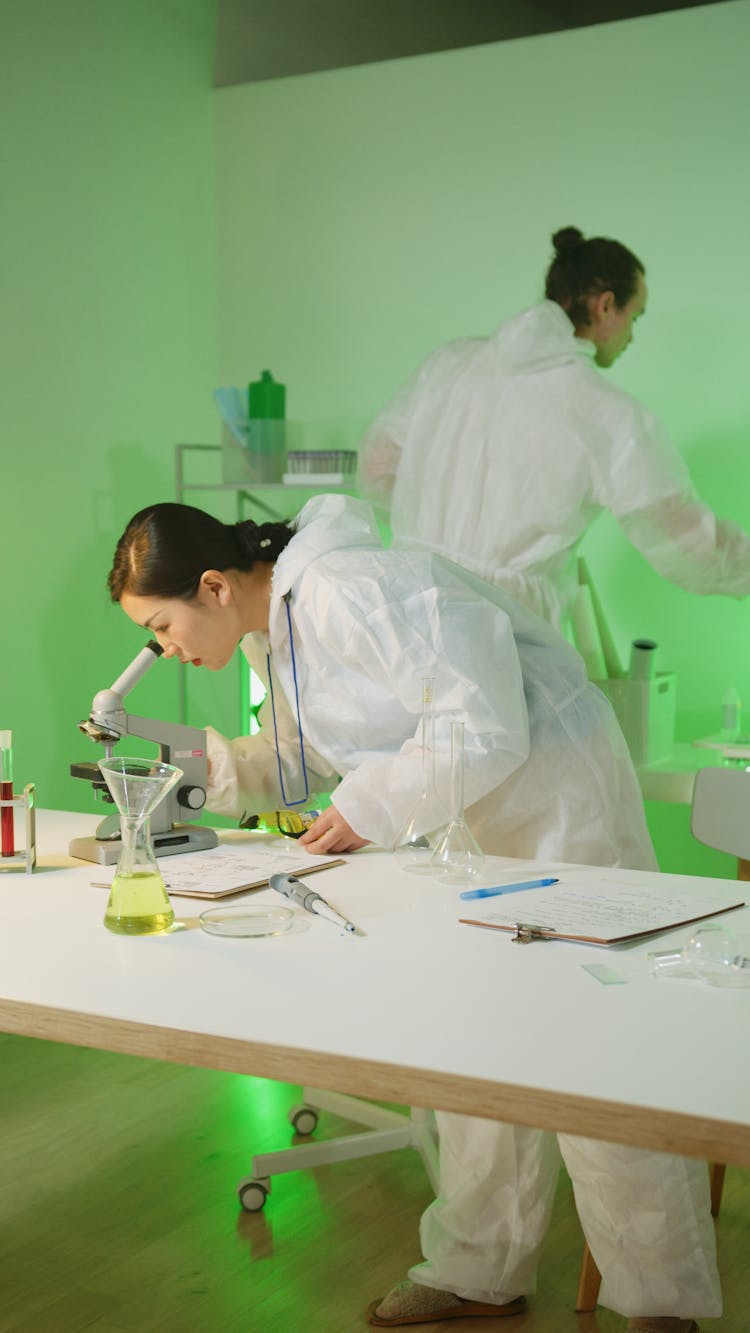 Scientists Examining Chemicals Inside A Science Laboratory Using A Microscope