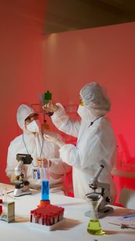 Two scientists in protective suits conduct experiments in a modern laboratory with microscopes and glassware.