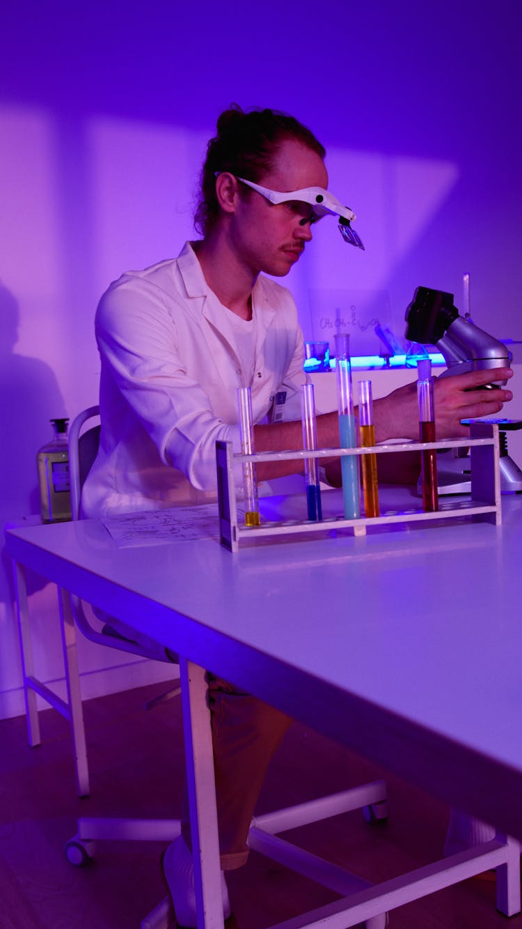 A Scientist Doing Experiment Using A Microscope