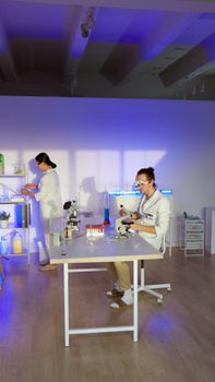 Two scientists examining samples in a modern laboratory setting with microscopes and test tubes.