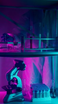 A scientist in protective gear working in a lab with microscope and test tubes.