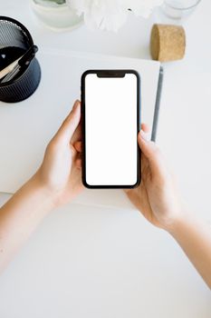 High-angle view of hands holding a smartphone with blank screen, ideal for mockups.