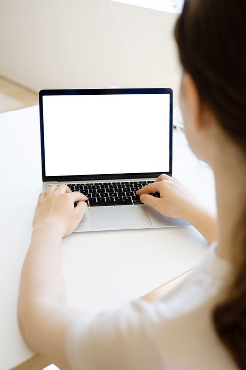 Free A woman typing on a laptop with a blank screen, ideal for mockups. Stock Photo