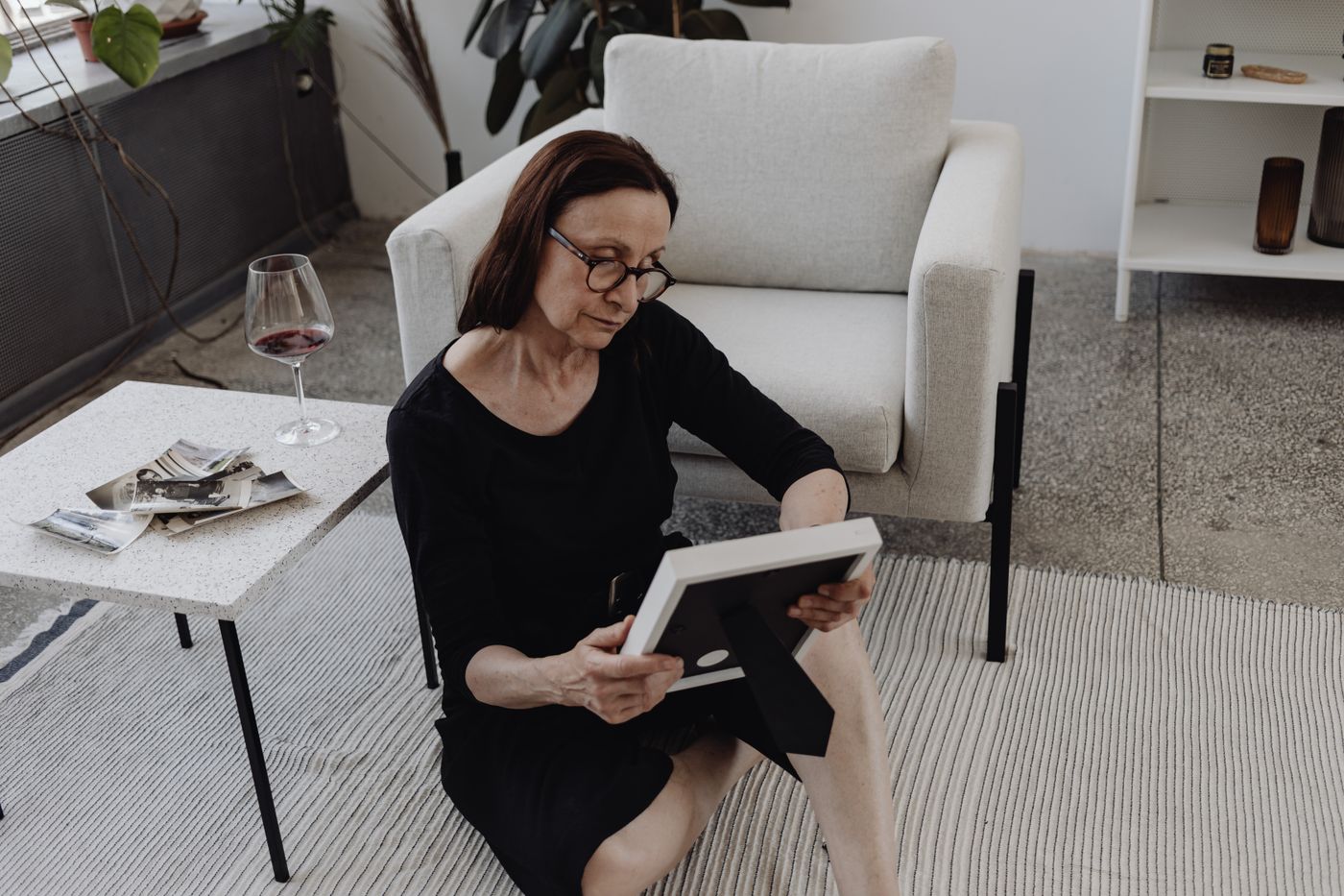 A grieving woman alone on the floor, holding a picture frame — the deep, invisible emotional pain of early pregnancy loss