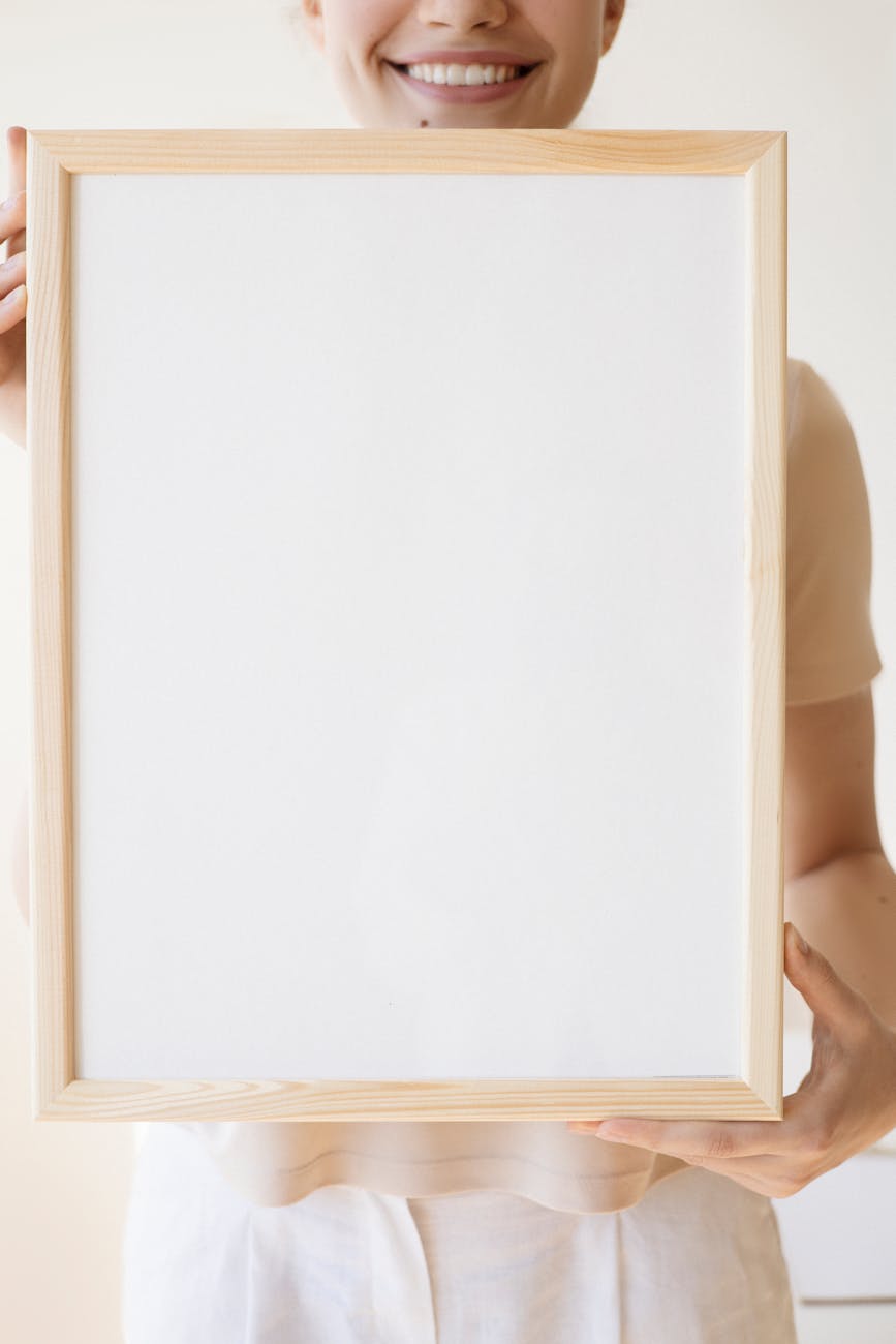 Smiling woman holding a blank framed canvas, perfect for copy space and personalized content.
