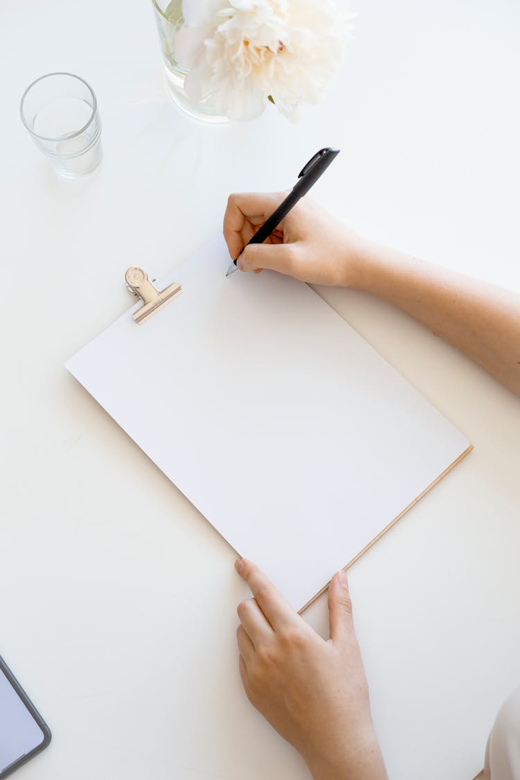 A Person Holding A Blank Paper On A Clipboard