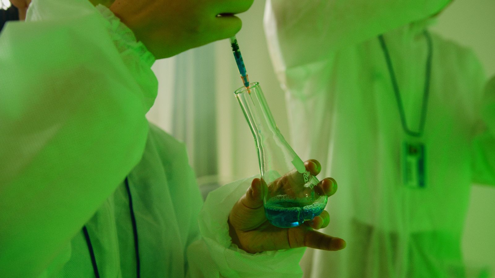Close-up of a scientist using a syringe to handle chemicals in a laboratory setting.