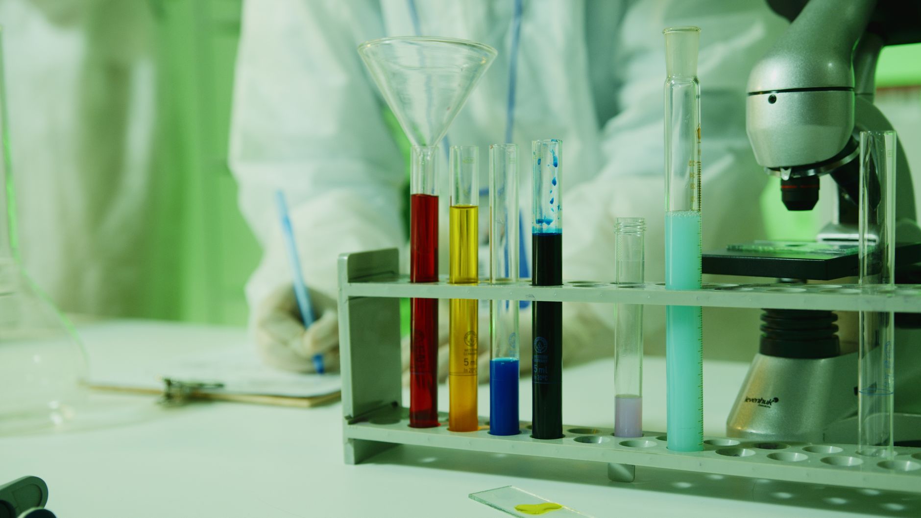Close-up photo of lab research setup with test tubes and a microscope.