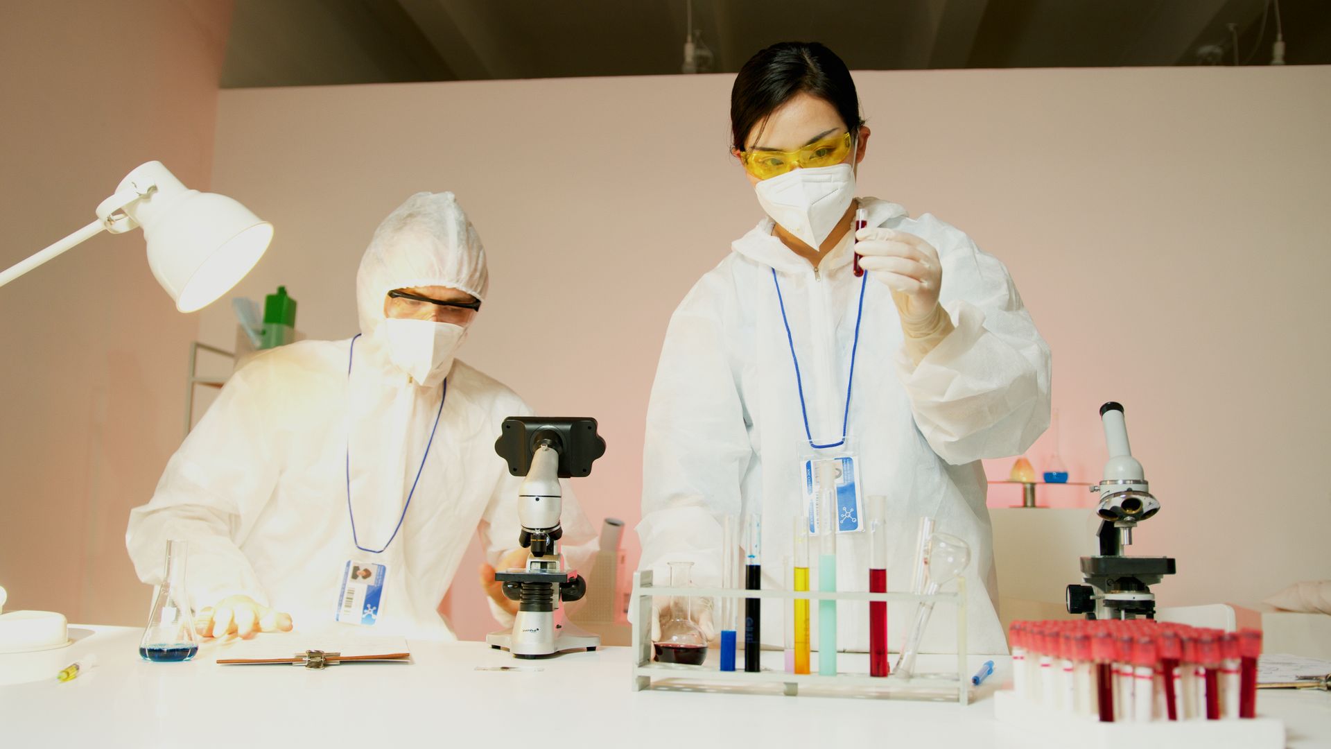 Scientists working with microscopes and test tubes in a laboratory setting.