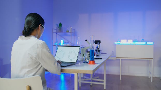 Female scientist studying chemical structures on a laptop in a modern laboratory setting.