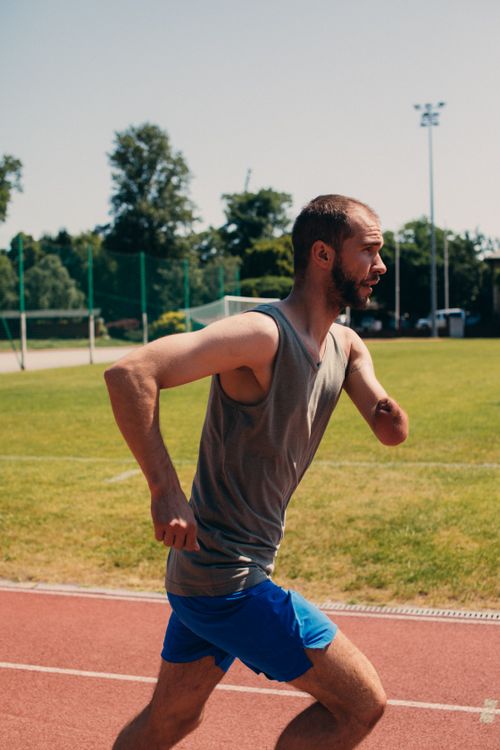 Free An inspiring image of an amputee athlete jogging on an outdoor running track, embodying strength and perseverance. Stock Photo