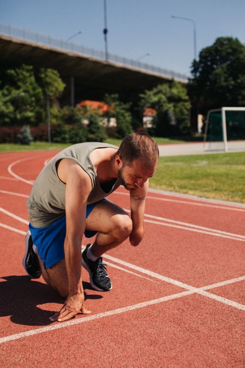 Free Man preparing to run on a bright day, showcasing determination and fitness. Stock Photo