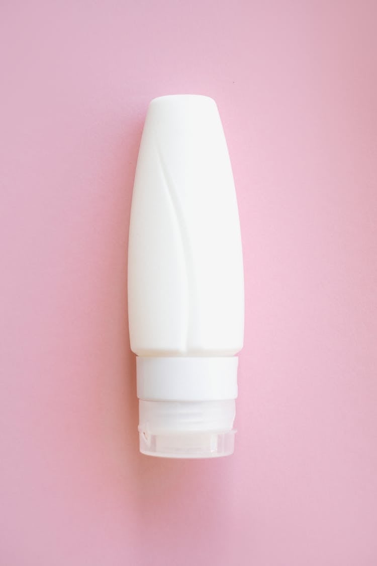 Close-Up Shot Of A Lotion Bottle On Pink Surface