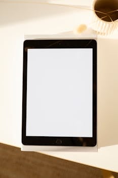 Top-down view of a blank screen tablet on a sunlit desk, perfect for design presentations.