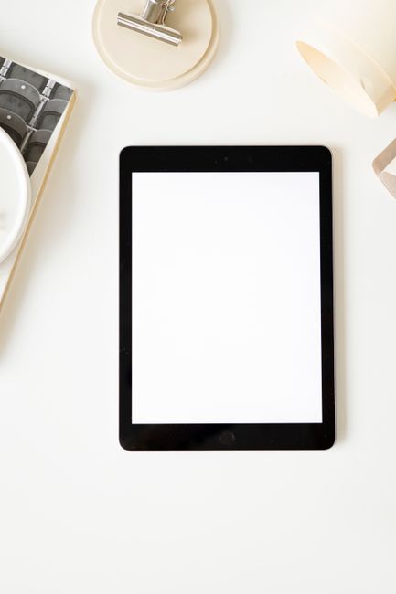 Top view of a minimalist workspace layout featuring a blank tablet screen for creative design purposes. Top view of a minimalist workspace layout featuring a blank tablet screen for creative design purposes.